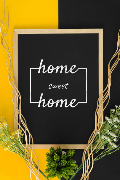 Home sweet home on black and yellow background with rustic wood sticks and flower. - Foto, Imagen