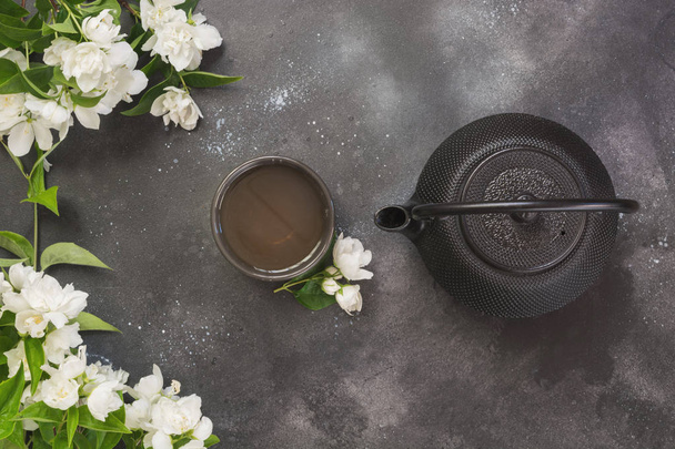 Green jasmin tea and jasmine flowers, cup of green tea on black. Top view and concept. Teatime. Copy space. - Φωτογραφία, εικόνα