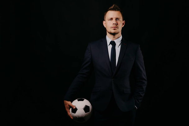 young handsome businessman holding a football on black background studio. - Foto, Imagen