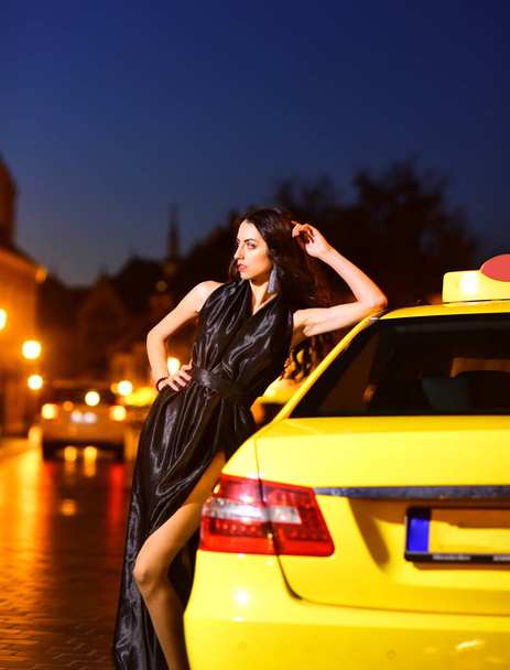 Night city with princess in celebrity style. Luxury woman in evening dress at night city go to prom on taxi. Girl with glamour makeup. Fashion and beauty of business lady. Sexy girl in elegant dress - Zdjęcie, obraz