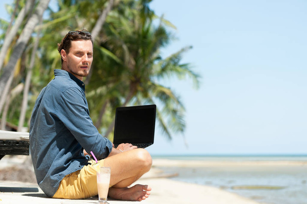 Ember szabadúszó laptop ül a strandon, és keresi a kamera - Fotó, kép