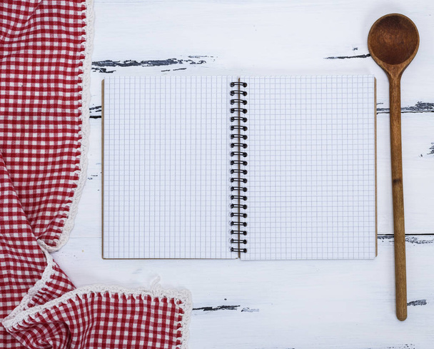 caderno vazio aberto com lençóis brancos e uma colher de madeira de cozinha na mesa, vista superior
 - Foto, Imagem