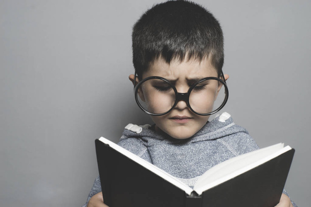 schoolboy, young student writing on a blackboard school with a book in hand and big glasses - 写真・画像