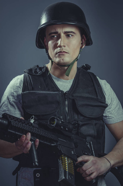 paintball sport player wearing protective helmet aiming pistol ,black armor and machine gun - Фото, изображение