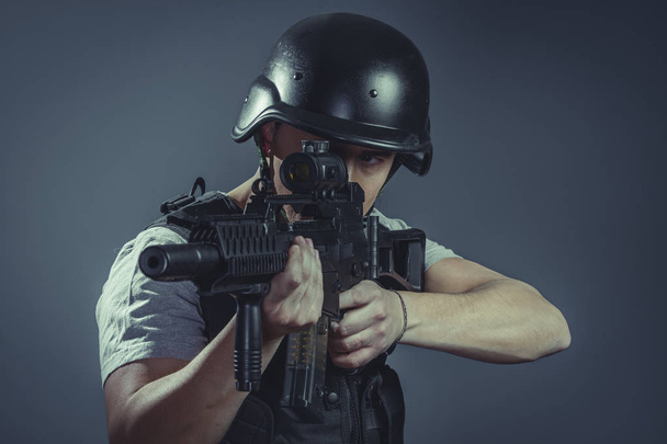 Targeting, paintball sport player wearing protective helmet aiming pistol ,black armor and machine gun - Fotó, kép
