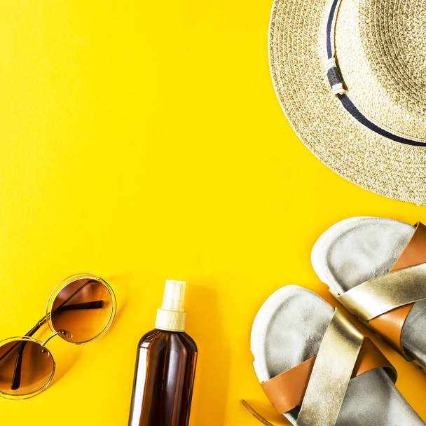 Akcesoria letnie damskie dla wakacji na plaży z słomkowy kapelusz, okulary słoneczne i krem do opalania na żółtym tle. Widok z góry, płaskie świeckich. Miejsce - Zdjęcie, obraz