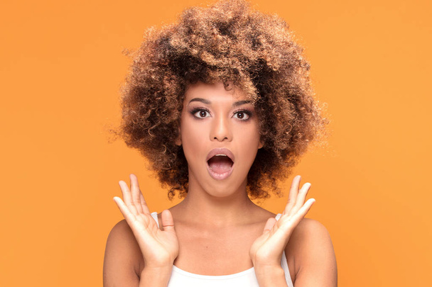 Surprised amazed beautiful afro woman looking at camera. Girl posing on yellow background. - Fotoğraf, Görsel