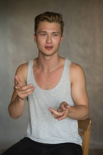 A shoot of young caucasian handsome blonde man against grey background. - Photo, Image