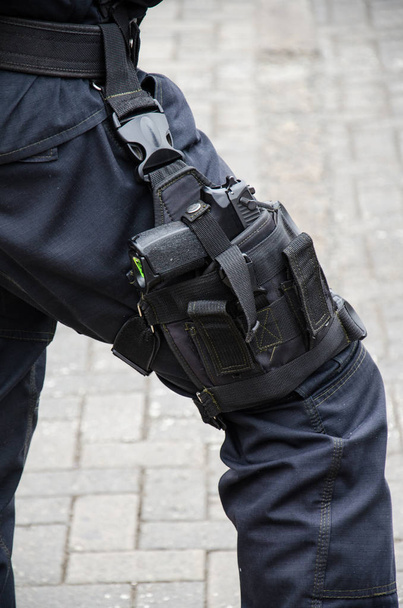 Pierna de un policía en la que se encuentra un arma de fuego
 - Foto, Imagen