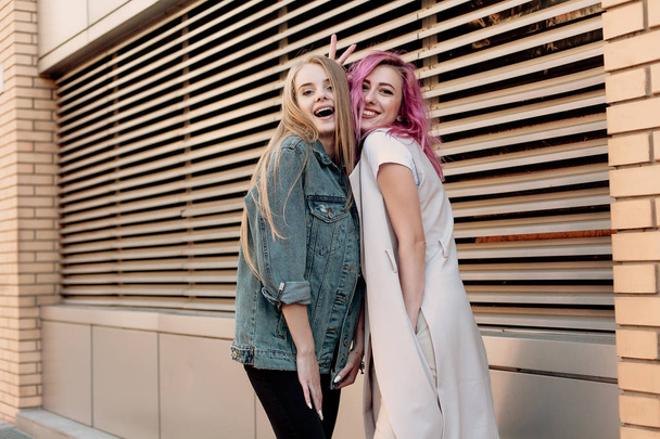 Hipster young adult friends embracing while hanging out in the city. Two young women laughing and walking enjoying carefree vacation lifestyle - Foto, afbeelding