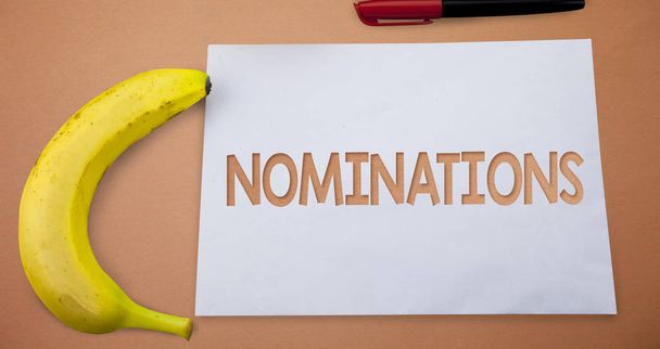 Text sign showing Nominations. Conceptual photo Suggestions of someone or something for a job position or prize Small paper drawing lines office work refreshment banana plane background - Photo, Image