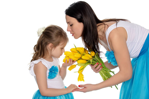 Moeder en dochter ruiken gele tulpen. - Foto, afbeelding