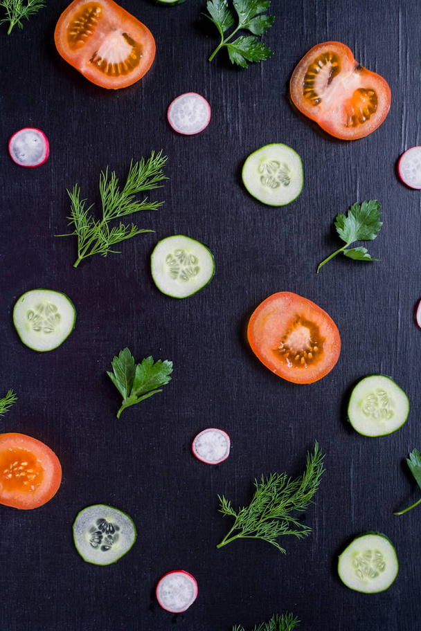 Pattern with sliced fresh vegetables on black background. Proper nutrition concept - Photo, Image