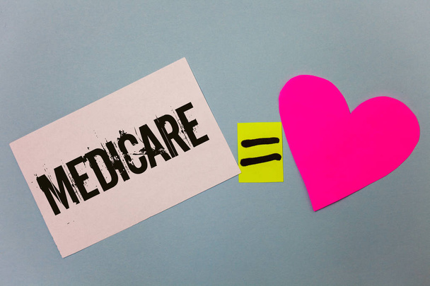 A kézírás szöveg írása a Medicare. Koncepció értelmében szövetségi egészségbiztosítási az emberek felett 65 vagy a fogyatékkal élők egyenlő szimbólum cetlik szív szeretet sík színes háttér kiszámítása - Fotó, kép