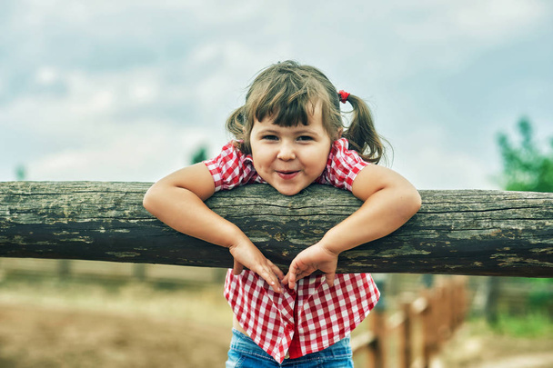 Lovely cheerful little girl on a walk .Girl in plaid shirt - Photo, Image