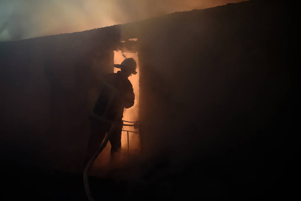 Silhouette of fireman fighting bushfire at night. - Foto, afbeelding