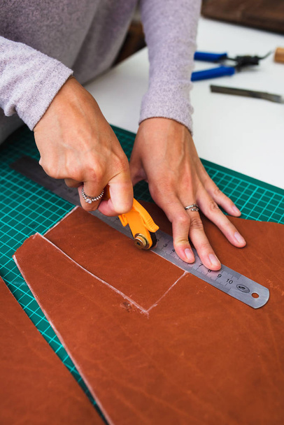 Closeup portrait of unrecognizable leather craftsman working making measupenets in patterns at table in workshop studio - Foto, Imagem