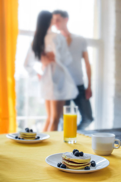 selectieve aandacht voor ontbijt op tafel en thuis verliefde paar - Foto, afbeelding