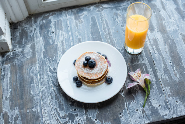 close up view of glass of juice and homemade pancakes for breakfast on wooden surface - Fotoğraf, Görsel