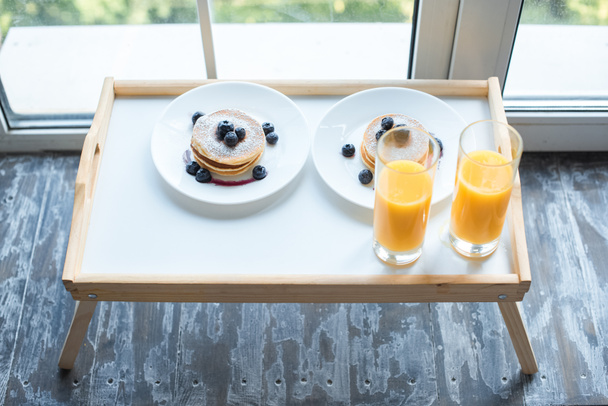 close up view of glass of juice and pancakes for breakfast on wooden tray - Foto, Imagem