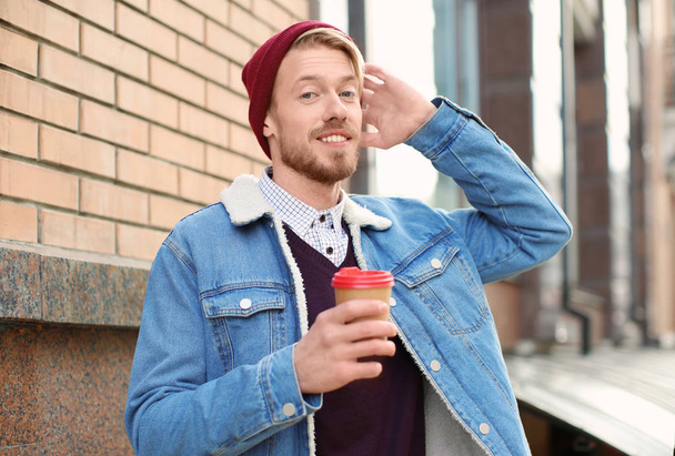 Portrait of trendy hipster drinking coffee outdoors - 写真・画像