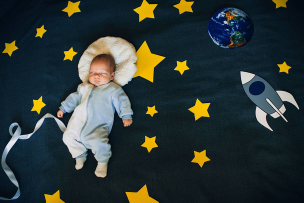 vauva poika nukkuu taustalla tähtitaivaan kanssa raketti ja planeetta
 - Valokuva, kuva