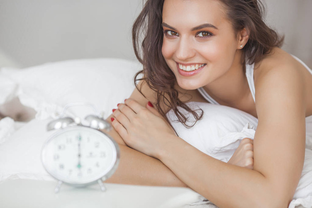 Beautiful young woman in the morning bed with alarm clock - Фото, зображення