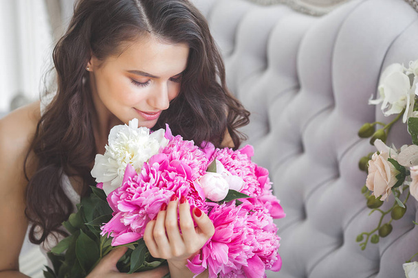 Very beautiful woman with flowers and gift indoors - Photo, Image