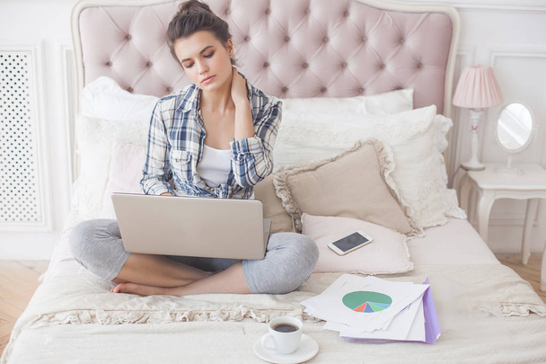 Jonge aantrekkelijke vrouw werken thuis achter de laptop - Foto, afbeelding