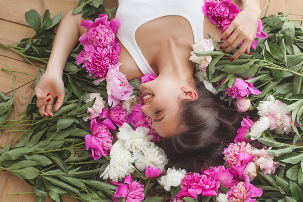Giovane donna attraente con fiori di peonia rosa e bianchi
 - Foto, immagini