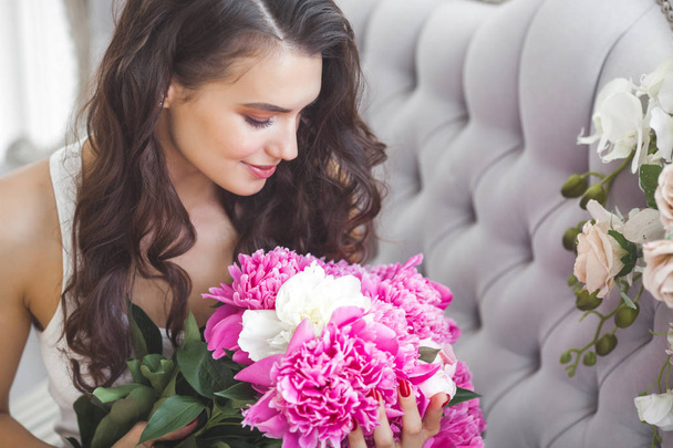 Young attractive woman with pink and white peony flowers - 写真・画像