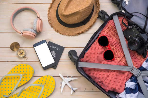 Cestovní pas, peněženka, brýle, zařízení chytrého telefonu, na dřevěné podlaze v zavazadlech připravených k cestování. - Fotografie, Obrázek
