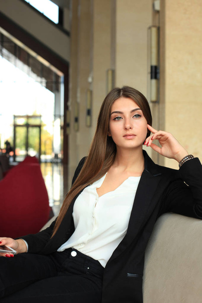 businesswoman sitting on sofa and using smartphone in coffee shop - Valokuva, kuva