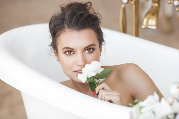 Young beautiful woman taking bath with flowers and milk - Φωτογραφία, εικόνα