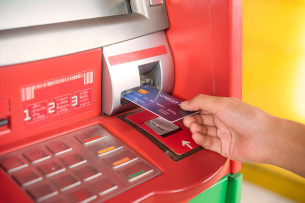Inserción manual con tarjeta de crédito en el cajero automático. Hombre usando un cajero automático con tarjeta de crédito para retirar dinero
 - Foto, Imagen