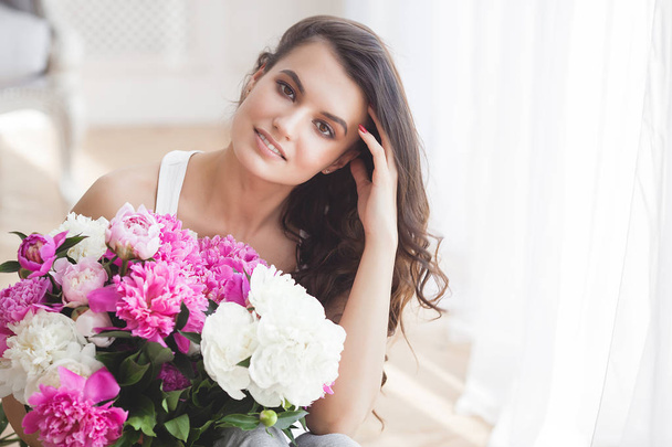 Jonge aantrekkelijke vrouw met roze en witte pioen bloemen - Foto, afbeelding
