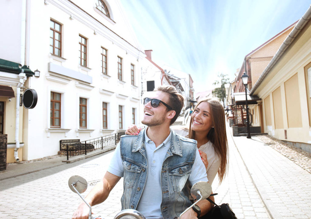 happy young couple riding scooter in town. Handsome guy and young woman travel. Adventure and vacations concept - Valokuva, kuva