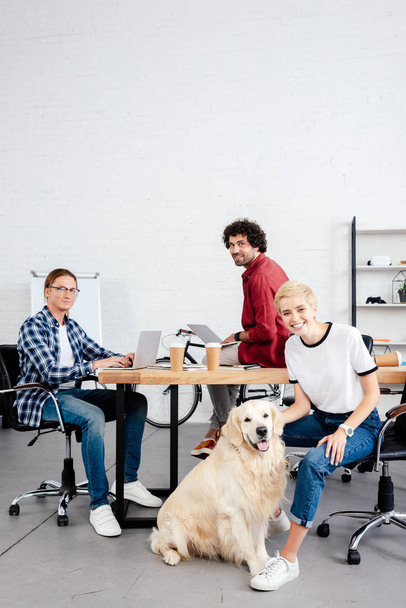 mladí nastartovat tým a psa při práci v kanceláři při pohledu na fotoaparát  - Fotografie, Obrázek