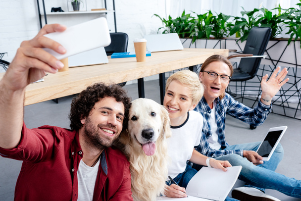 Lächelnde junge Leute machen Selfie mit Labrador im Büro  - Foto, Bild