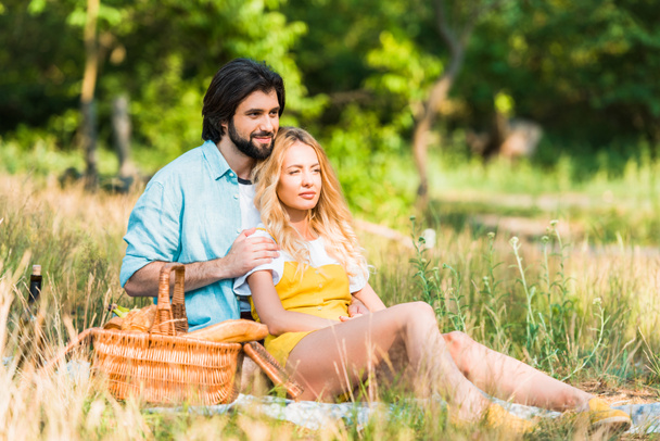 affectionate couple hugging and sitting on grass at picnic - Foto, Imagen