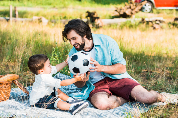 όμορφος γιος πατέρας και παιδί παίζουν με την μπάλα ποδοσφαίρου στο πικ-νικ - Φωτογραφία, εικόνα