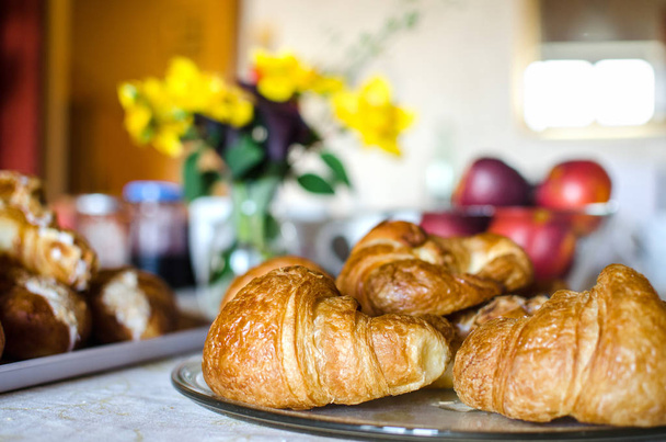 Croissants francés fresco en la mesa de desayuno con flores y frutas. Tradicional
. - Foto, Imagen