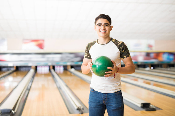 Adolescent masculin beau avec boule de bowling verte à l'allée dans le club
 - Photo, image