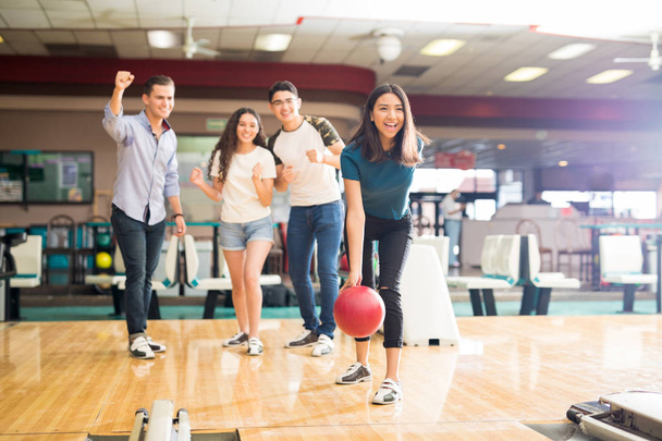 Pełna długość przyjaciół, motywowanie teen dziewczyna rzucanie piłki bowling Alley w klubie  - Zdjęcie, obraz