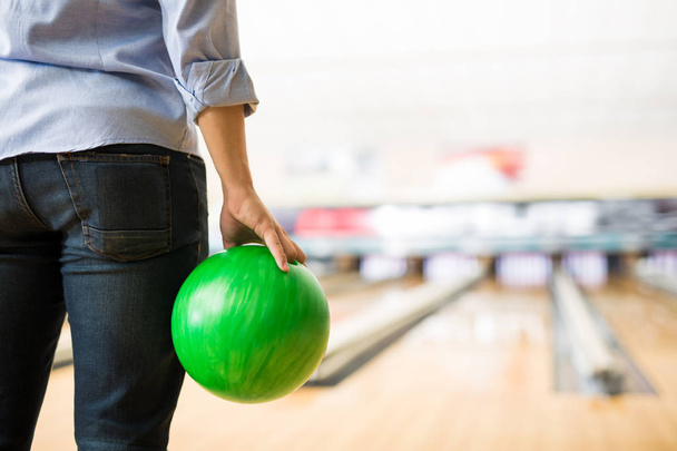 teenage boy practicing bowling with green ball in club - Foto, imagen