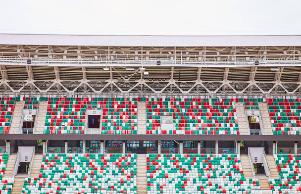 Lege tribunes van een modern stadion zonder toeschouwers en gekleurde stoelen in het midden van de aren - Foto, afbeelding