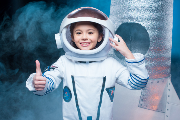 bambino sorridente in costume da astronauta facendo pollice in su gesto
  - Foto, immagini