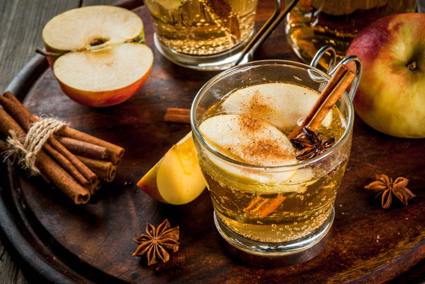 Herfst- en wintermaanden drankjes. Traditionele huisgemaakte appel cider, cocktail van cider met aromatische kruiden - kaneel en anijs. Op een oude houten rustieke tafel, op een dienblad. Kopiëren van ruimte - Foto, afbeelding