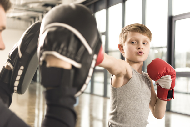petit boxeur enfant pratiquer des coups de poing avec l'entraîneur à la salle de gym
 - Photo, image