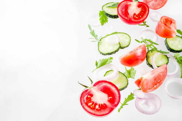 Creative background, layout, concept of fresh healthy diet of salad, fresh raw  vegetables tomatoes parsley onions cucumbers greens, simple pattern on white background - Photo, Image